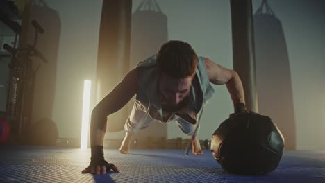 man doing push-ups with medicine ball in gym