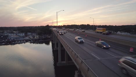 drone shot tracking forward next to interstate on bridge at sunset, with light traffic flow