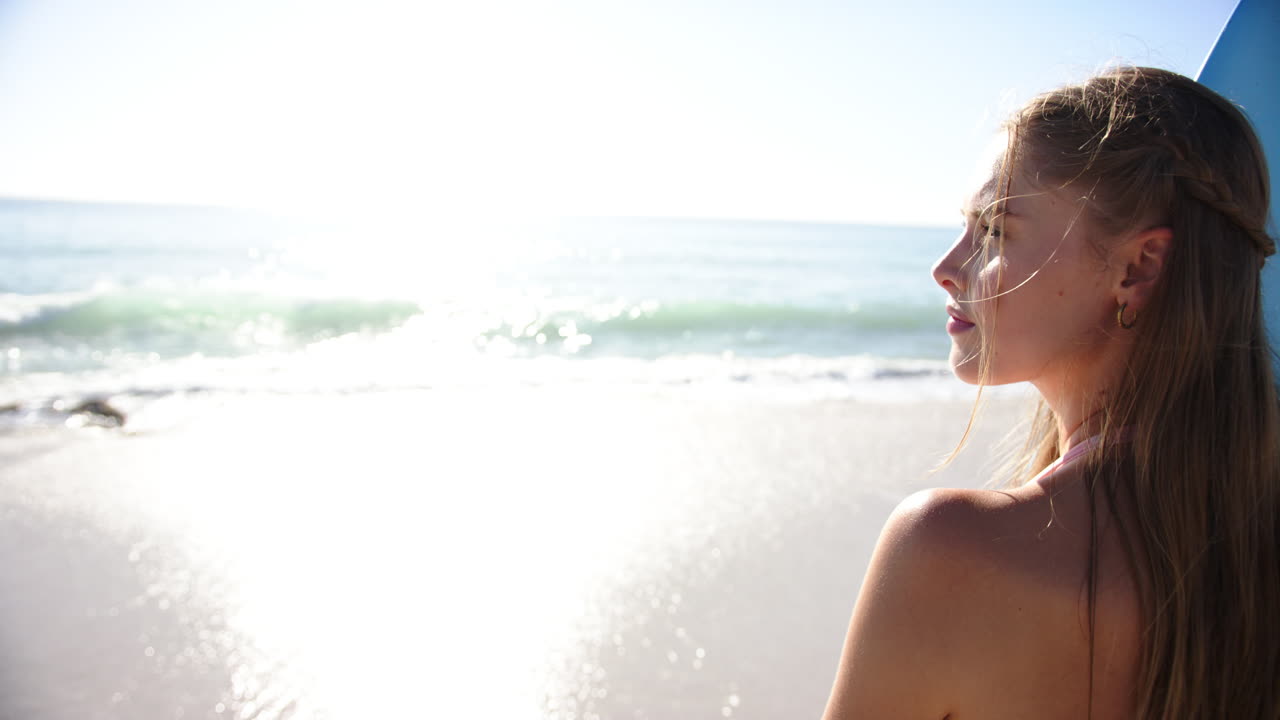 A young Caucasian woman gazes at the ocean horizon with copy space