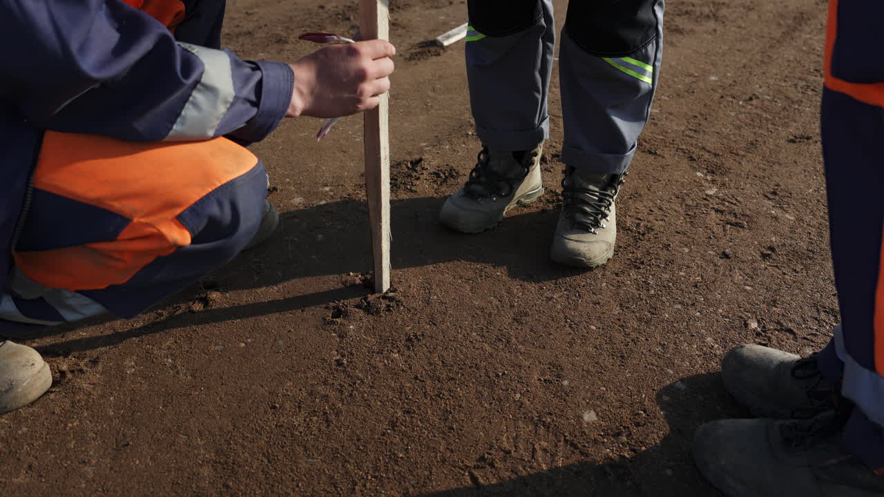 Workers measuring or marking on a dirt ground at a work site