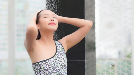 standing in the shower a young attractive woman in a bathing suit washes off the chlorine from the pool