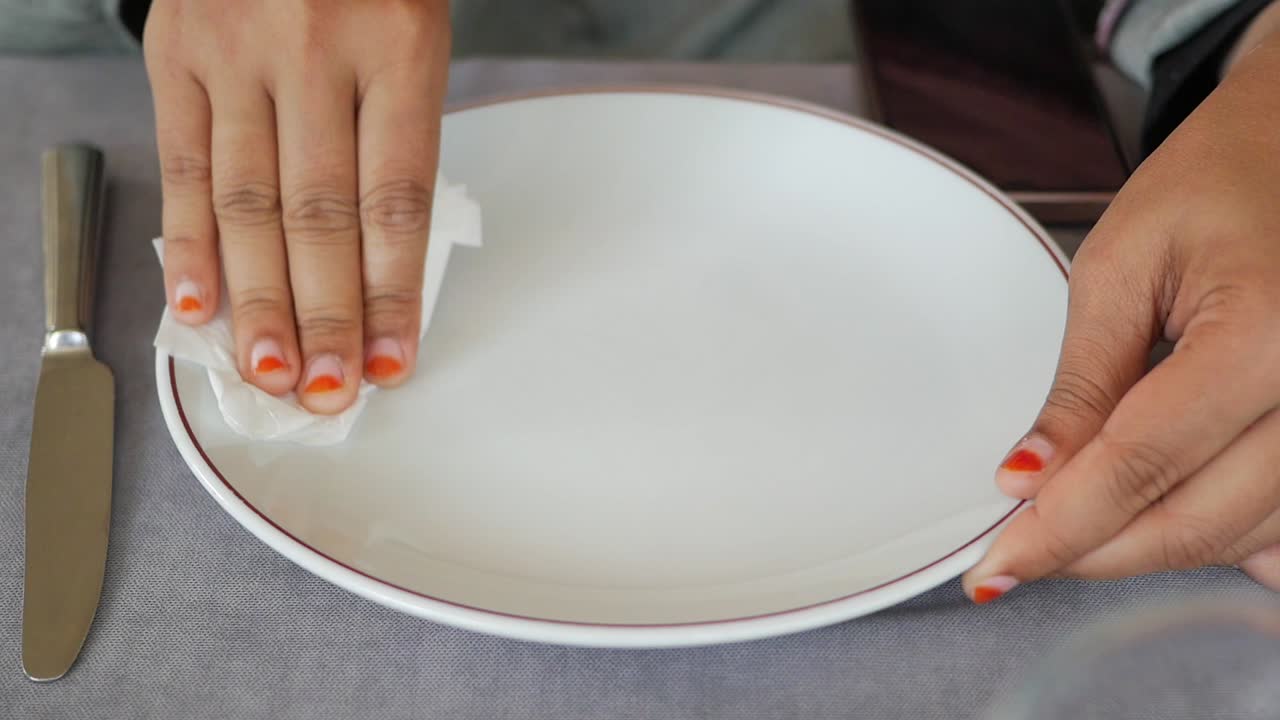 mujer limpiando un plato con una servilleta
