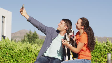 happy caucasian couple spending time outside with their dog