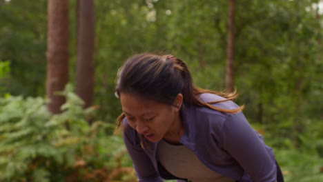 tired mid adult woman exercising doing work out outdoors running along track through forest stopping to catch breath shot in real time 1