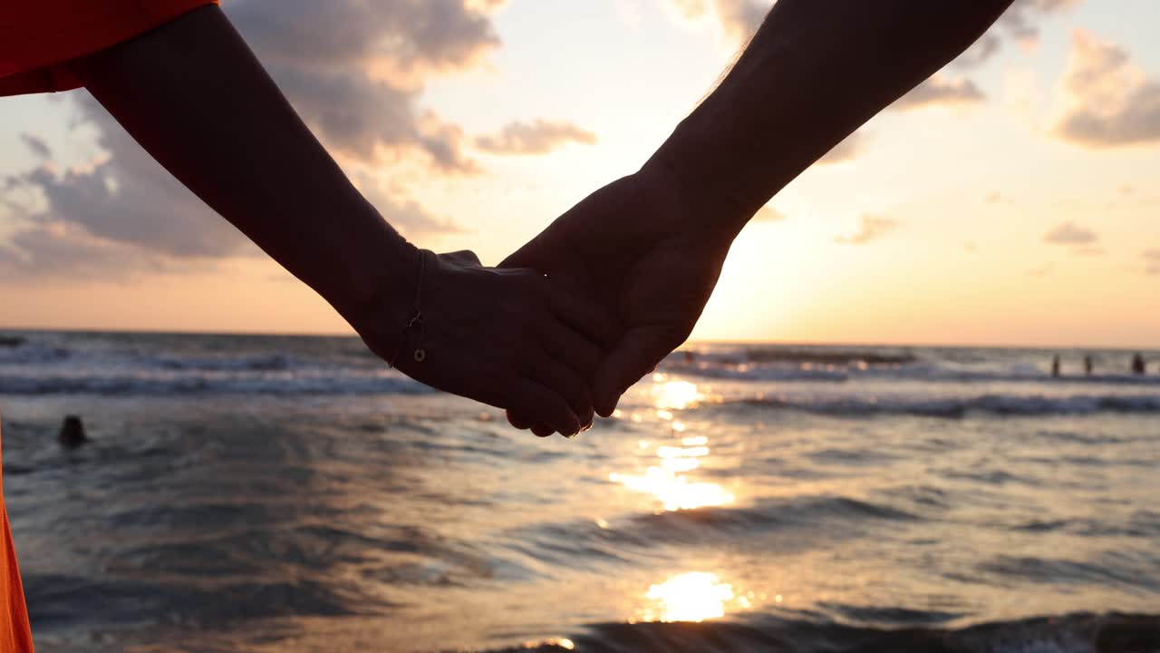 pareja de manos en la puesta de sol en la playa