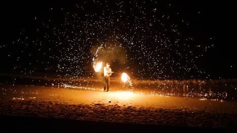 performer displays fire skills on sandy beach