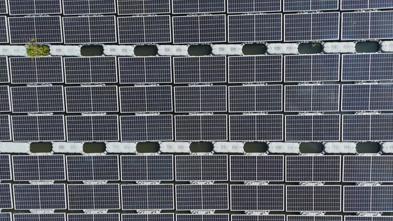 A top-down, overhead drone shot of Malaysia's largest floating solar farm on Danau Tok Uban, Kelantan, showing the geometric grid pattern of solar panels on the water's surface