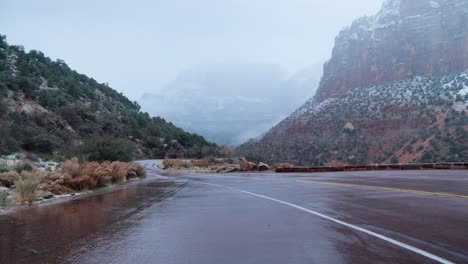 Wide-shot-of-the-Red-roads-in-Zion-National-Park-getting-covered-by-the-snow-fall-on-a-foggy-day