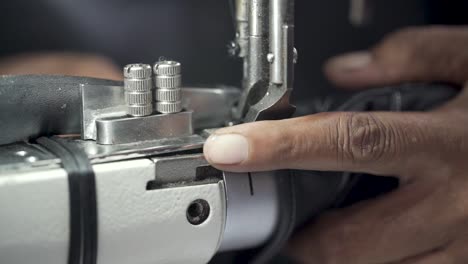 closeup shot of a tailor stitching leather, sewing machine in clothing production