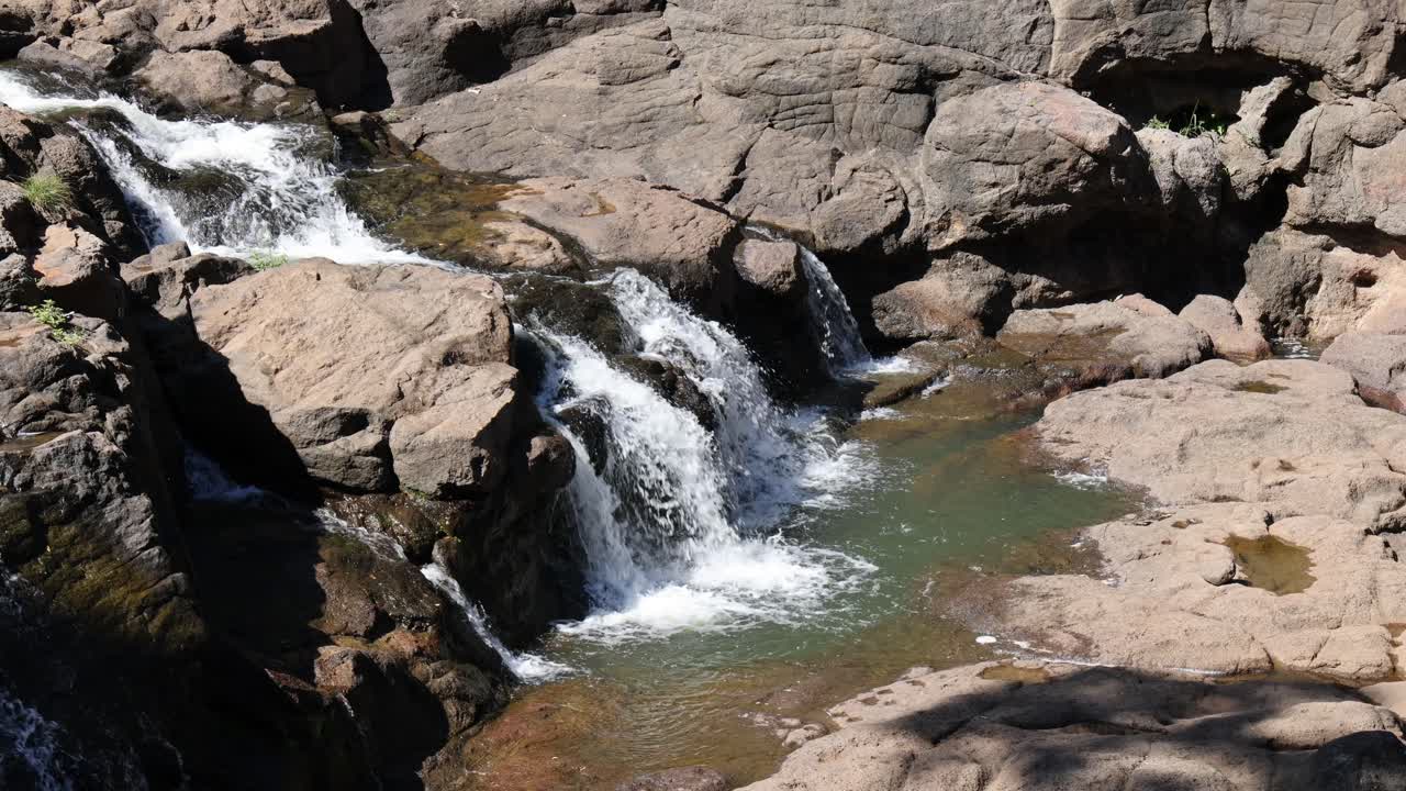 Cascada de agua sobre rocas en un entorno natural