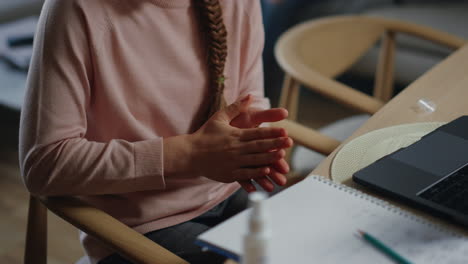 Unknown-girl-disinfecting-hands-before-online-class.-Student-applying-sanitizer.