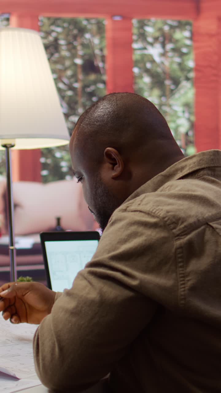 Focused African American Man Analyzing Blueprints on Tablet