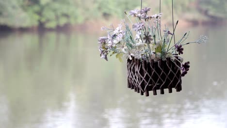 a decorative flower pot hanging from a house boat floating on a river, a natural setting embracing the beauty of nature in kanchanaburi, thailand