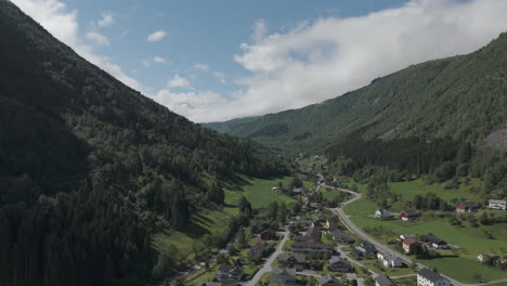 drone shot flying in between the mountains with a small village on the ground on a sunny and cloudy day log