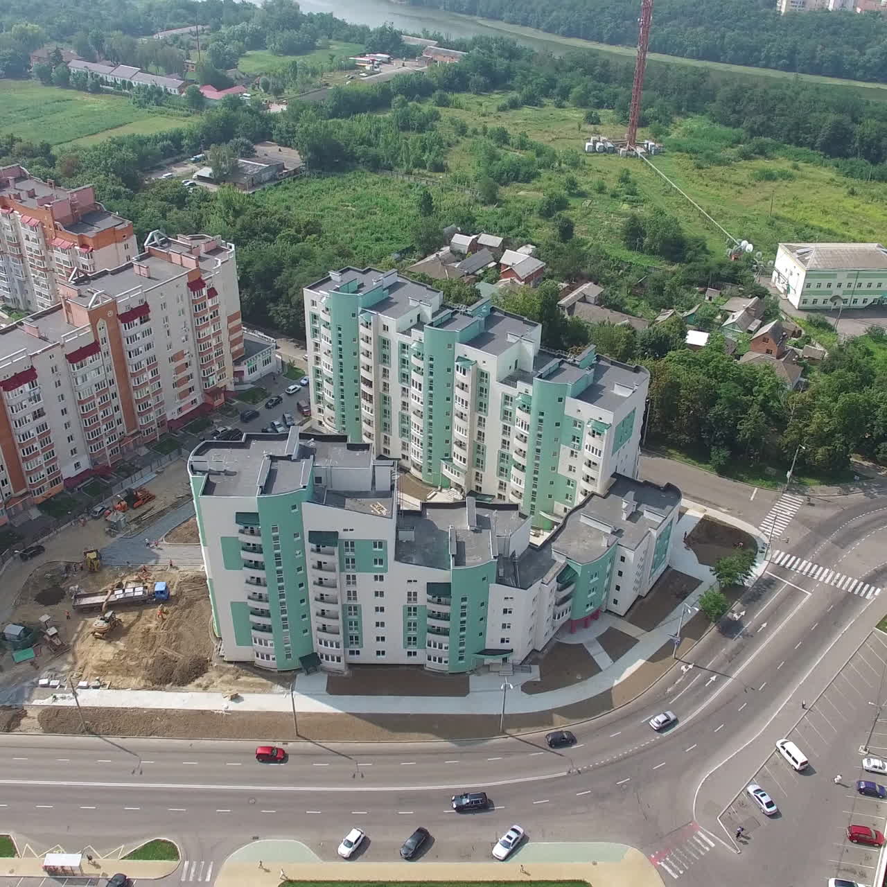 Flying over the modern residential buildings and green trees in the town. New houses with residential apartments. Aerial view