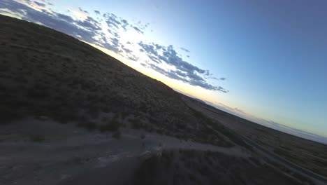drone de fpv sobrevolando rápidamente el desierto y las montañas en el paso, tx al atardecer