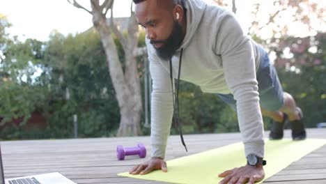 Konzentriertes-Afroamerikanisches-Mann-Fitnesstraining-Beim-Liegestütztraining-An-Deck-Im-Sonnigen-Garten,-Zeitlupe