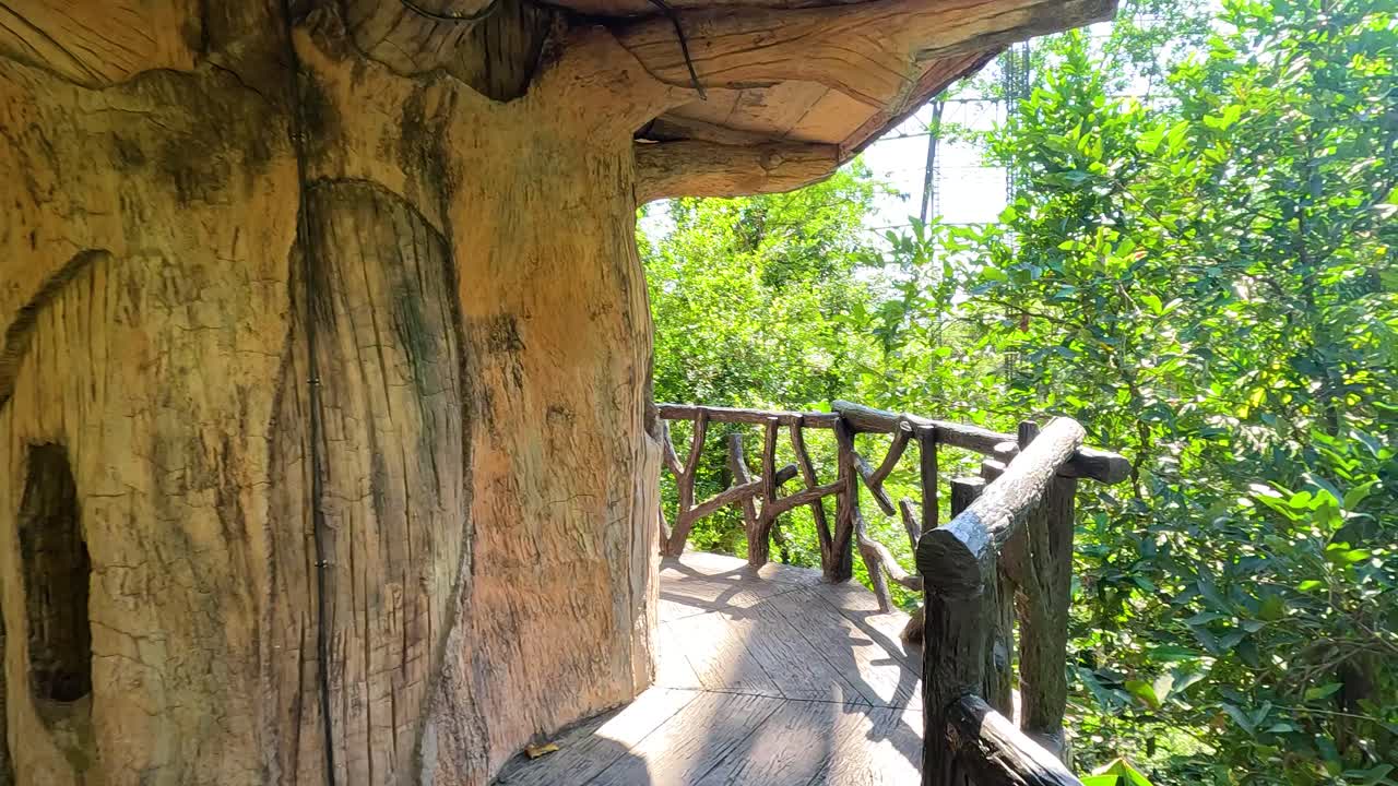 A serene walkway in a lush aviary, surrounded by vibrant greenery and natural wooden structures under bright daylight