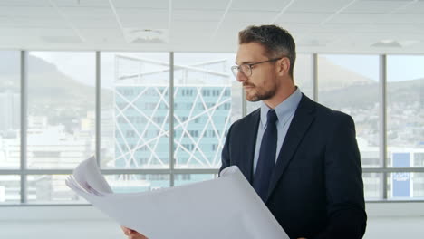 Male-Architect-In-Modern-Empty-Office-Looking-At-Plans