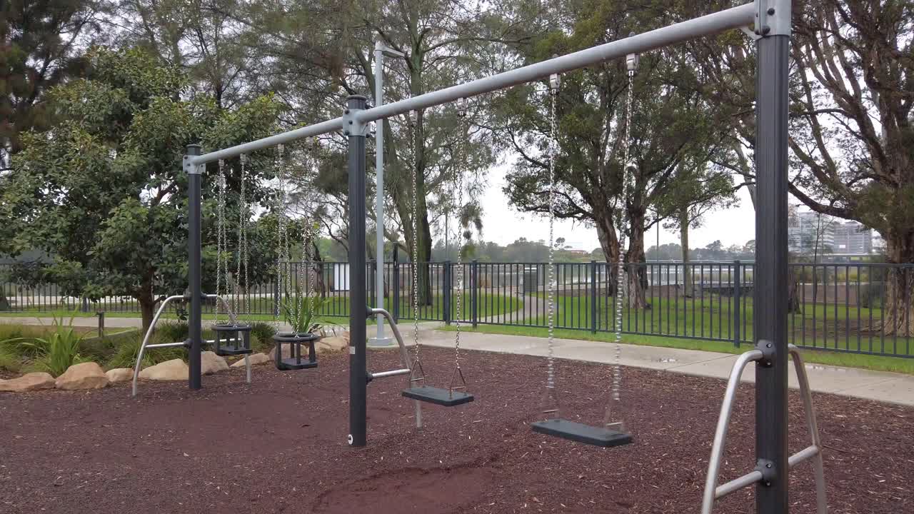 Empty children swings in the kids playground at the park