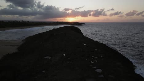 el atardecer sobre la playa de arecibo puerto rico con un dron sobre una orilla rocosa 2