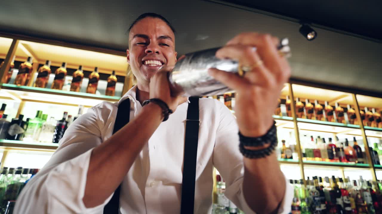 Barman felice che agita uno shaker per cocktail dietro un bancone