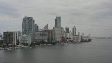 Toma-Aérea-Que-Se-Eleva-Desde-El-Agua-Mostrando-Edificios-En-El-Centro-De-Miami-A-Lo-Largo-De-La-Bahía