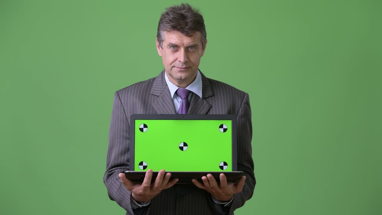 hombre de negocios maduro y guapo contra un fondo verde