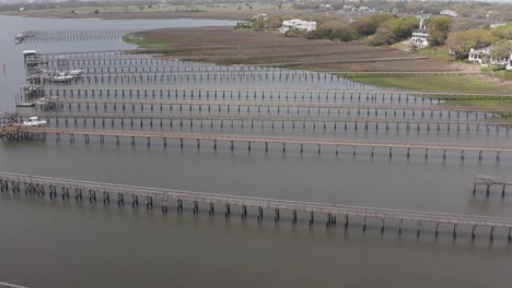 Low-tilting-up-aerial-shot-of-long-fishing-docks-off-historic-Old-Village-Mount-Pleasant,-South-Carolina