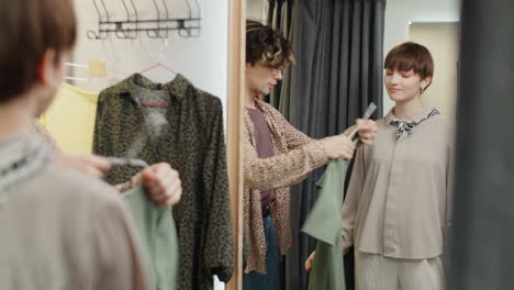 assistant helping female customer with choosing dress in fitting room