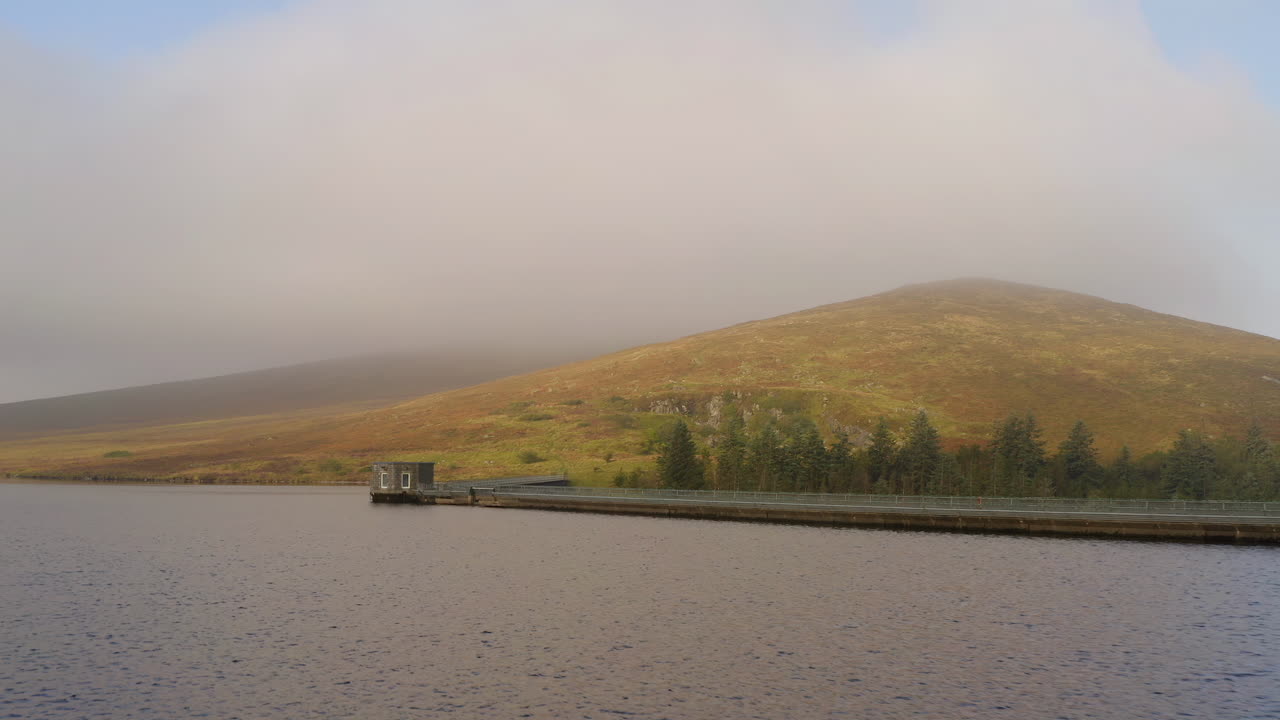 Dolly shot over the water of the control tower on the Spelga Dam