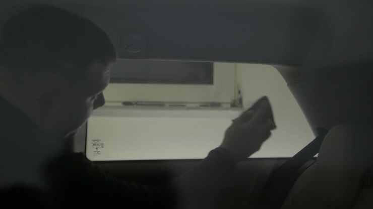 Vetro laterale dell'auto che viene oscurato con pellicola. Rimozione delle bolle d'aria.