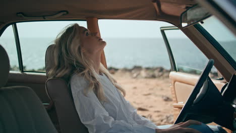 stressed woman finish call sitting at car helm on seashore closeup. girl worried