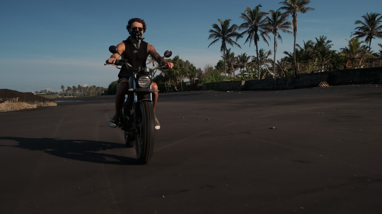 Man Riding Motorcycle on Black Sand Beach