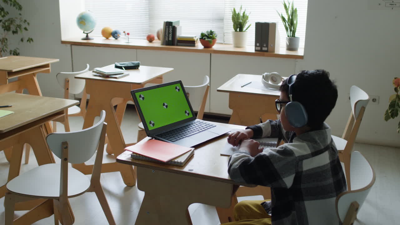 Boy Watching Green Screen on Laptop in Classroom