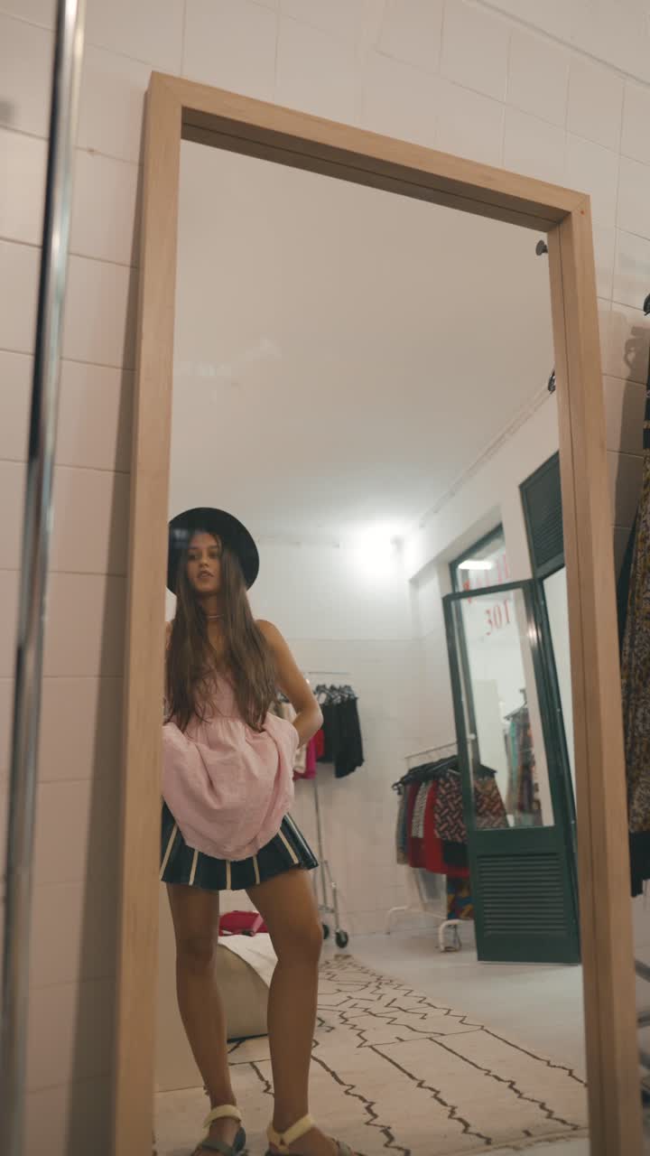 Donna con gonna e cappello in piedi davanti a uno specchio