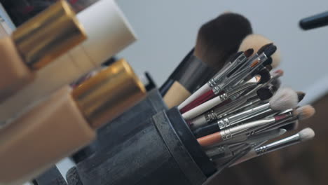 makeup artist takes fluffy brush to serve client in salon