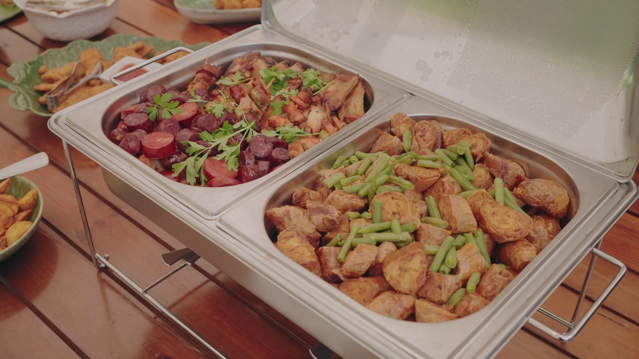 Buffet trays filled with roasted potatoes with green beans and sausage stew with herbs