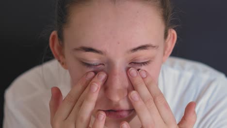 teenage girl applying eye cream or lotion close-up