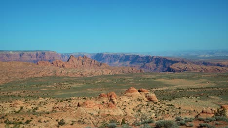 tilt up pan right extreme wide landscape shot revealing a dry desert landscape with colorful mountains and plateaus covered in sage brush on a hike in arizona, usa during a warm sunny spring morning