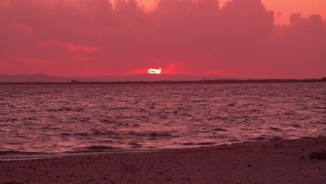 astonishing pink sky sunset at sea beach, waves crashing against sandy shore, zoom in