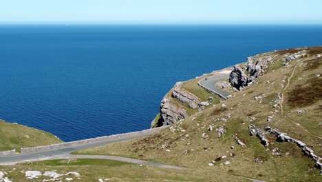 scenic green hikers landmark mountain country road overlooking gorgeous blue irish sea aerial view dolly left