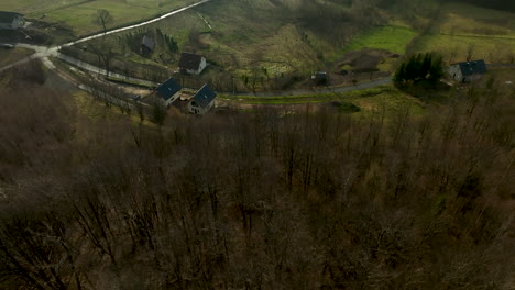 Un-Camino-Sinuoso-Serpentea-A-Través-De-Un-Paisaje-Rural-Diverso,-Salpicado-De-Casas-En-Construcción,-En-Medio-De-Campos-Y-Zonas-De-Bosque,-En-Un-Día-Nublado