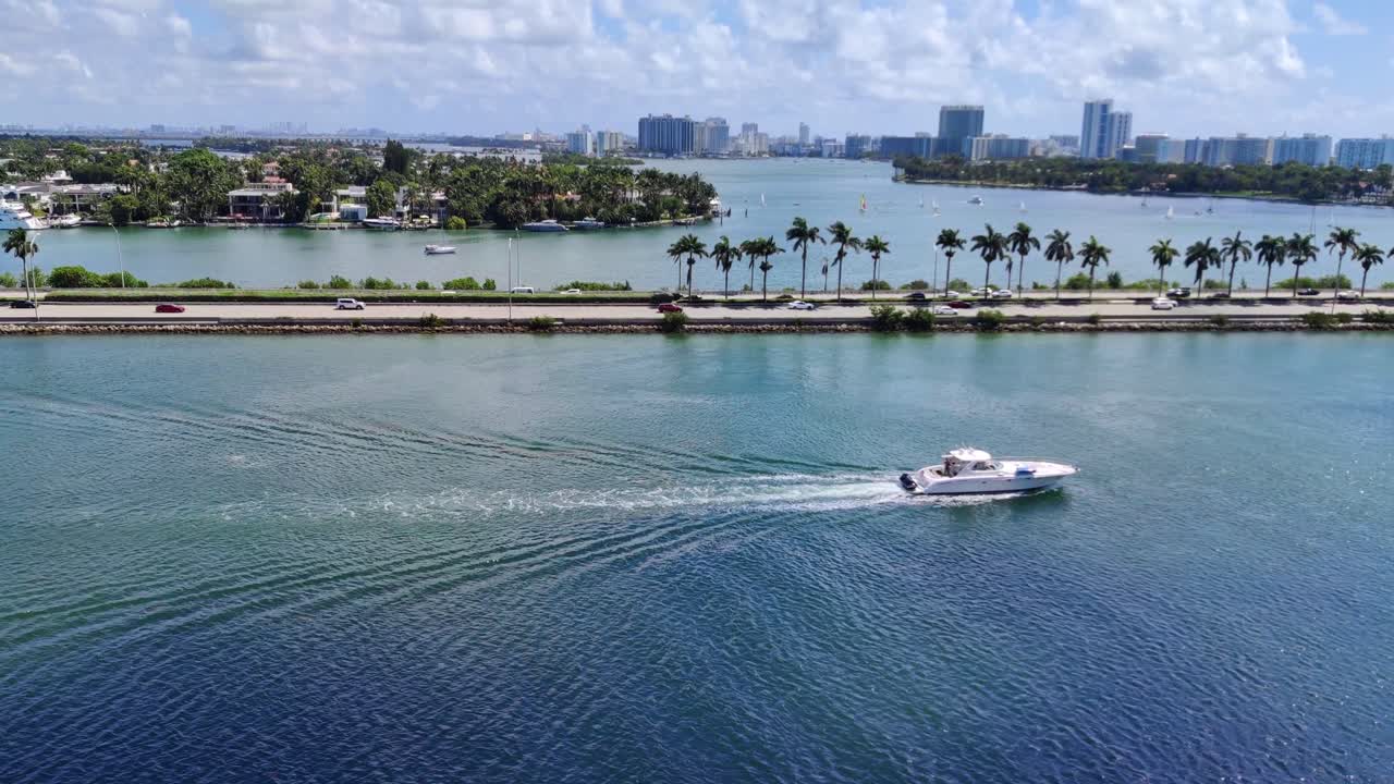velero moviéndose en la bahía de biscayne junto a la carretera de la calzada con automóviles y autobuses en el fondo de video de la carretera en 4k | velero en la bahía de miami con la carretera de la calzada y la isla de la palma del paisaje urbano