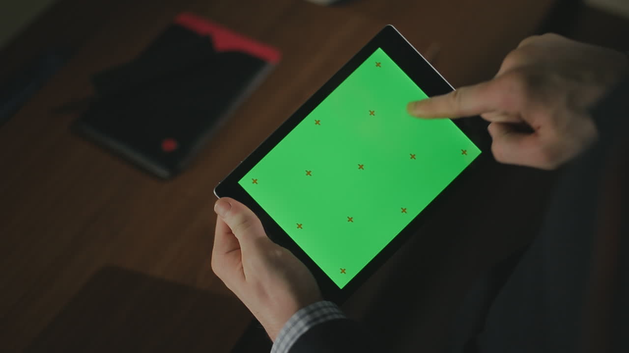 mano masculina usando una tableta con pantalla verde. dedo masculino tocando la pantalla de la tableta