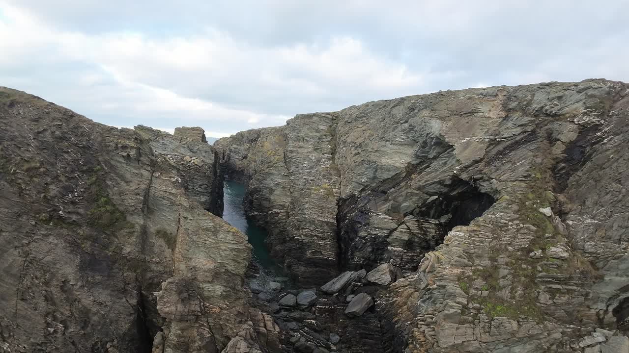 FPV aerial flying rocky welsh coastal cliff edge and mountain headland landscape