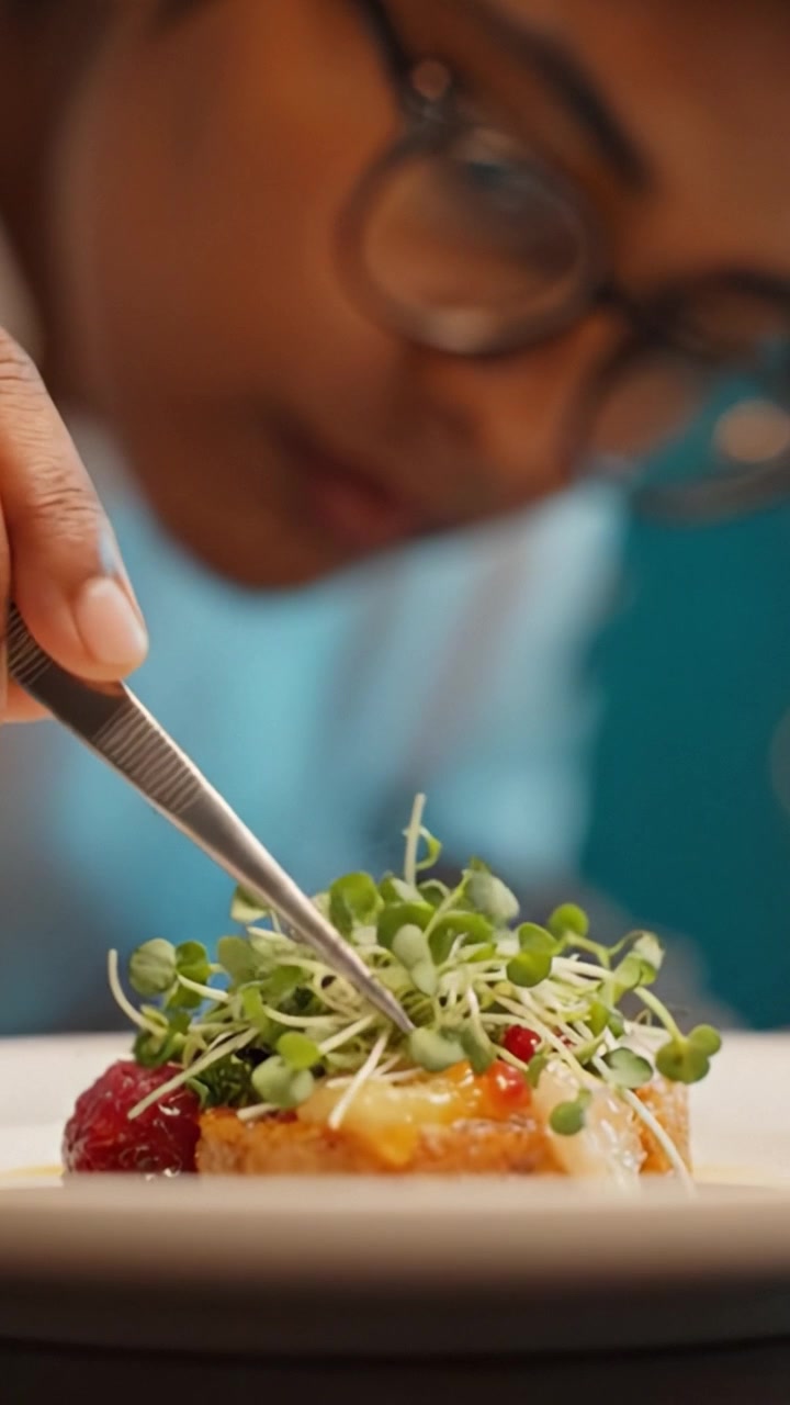 Culinary Artisan Engaged in Plating Gourmet Dish with Fresh Microgreens, Showcasing Attention to Detail in Food Presentation and Culinary Skills