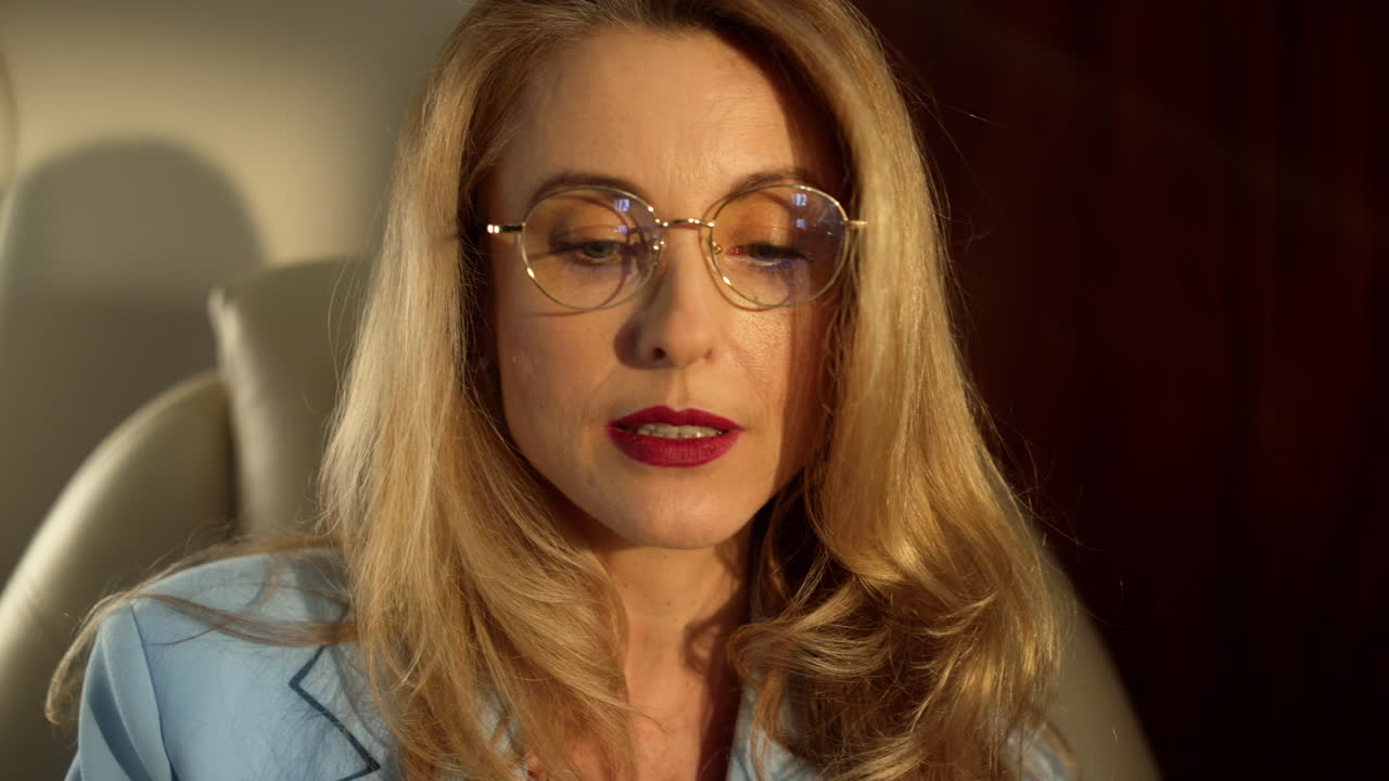 Closeup business couple discussing newspaper on airplane trip in golden sunlight