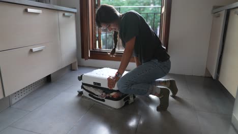 woman packing a suitcase in a kitchen