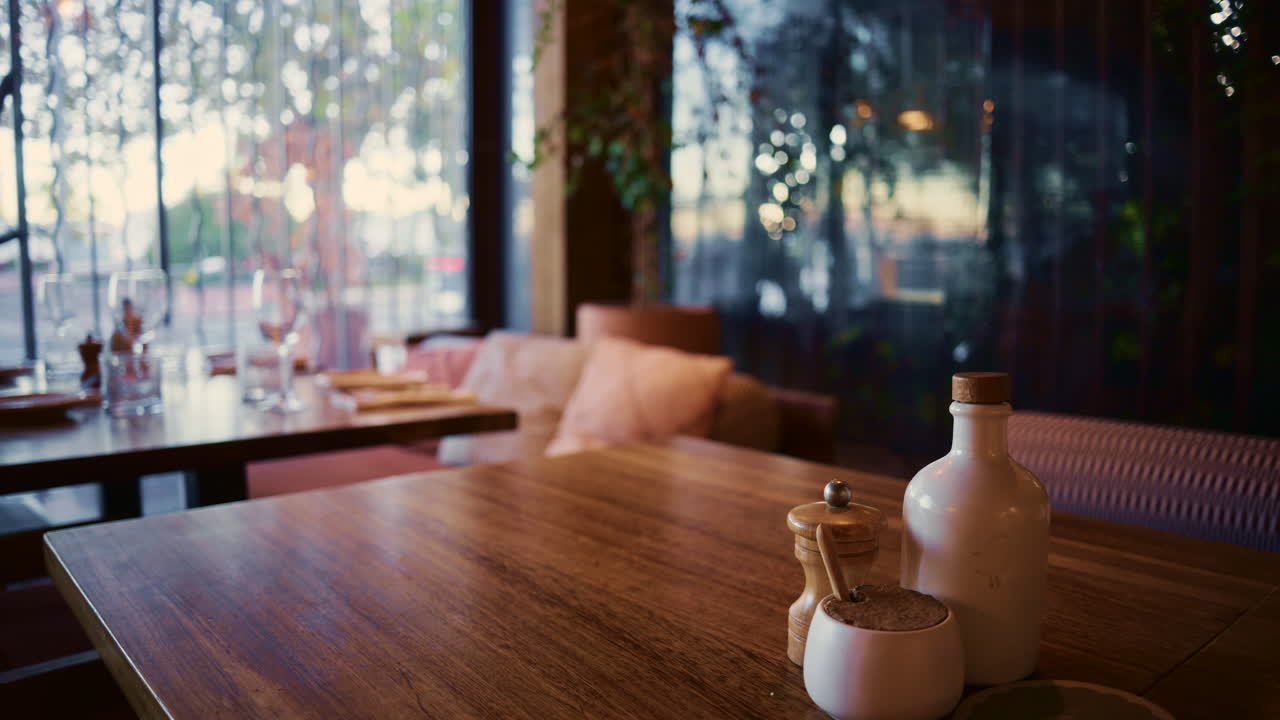 Warm and inviting restaurant interior, featuring a wooden table set with salt and pepper mills, soft lighting